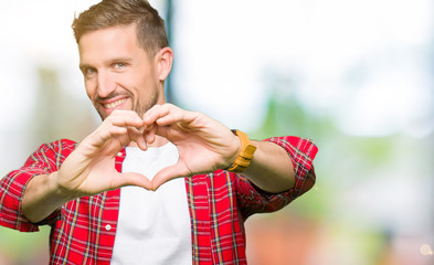 Handsome man wearing casual shirt smiling in love showing heart symbol and shape with hands. Romantic concept.
