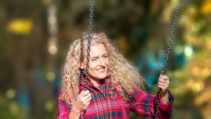 cheerful young woman has fun on swing