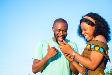 satisfied boyfriend and girlfriend checking interesting content on their mobile phone, celebrating  after receiving salary notification 