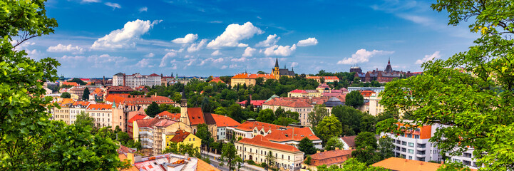 Fototapeta premium View of Prague Castle over red roof from Vysehrad area at sunset lights, Prague, Czech Republic. Scenic view of Prague city, Prague castle and Petrin tower from Vysehrad overlooking red roofs