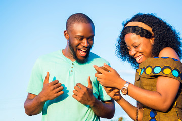 satisfied boyfriend and girlfriend checking interesting content on their mobile phone, celebrating ...
