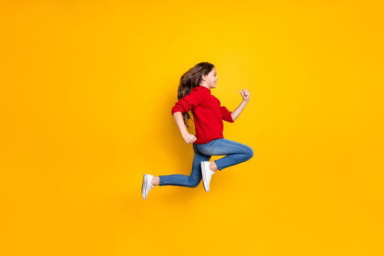 Full length profile side photo of positive cheerful brunette wavy curly hair kid jump run fast speedy after winter season discounts wear style clothes white sneakers isolated yellow color background