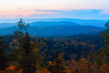 Fototapeta premium Evening mountain landscape. Mountains rocks trees against the setting sun. Krasnoyarsk National Park Pillars.