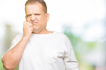 Middle age arab man wearig white t-shirt over isolated background looking stressed and nervous with hands on mouth biting nails. Anxiety problem.