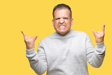 Middle age arab man wearing sport sweatshirt over isolated background shouting with crazy expression doing rock symbol with hands up. Music star. Heavy concept.