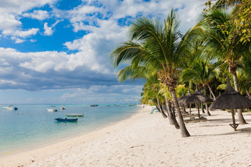 Fototapeta na wymiar Beautiful view of luxury beach in Mauritius. Transparent ocean with boats, beach, coconut palms and sky