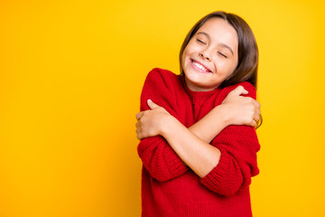 Portrait of peaceful calm kid hug embrace herself enjoy warm soft comfy sweater pullover wear red stylish lifestyle clothes isolated over yellow color background