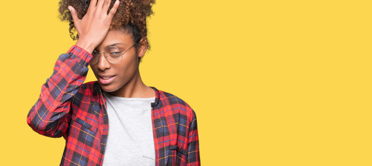 Beautiful young african american woman wearing glasses over isolated background surprised with hand on head for mistake, remember error. Forgot, bad memory concept.