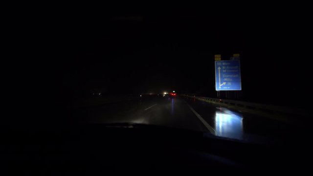 4K weather footage, inside view out from car driving through heavy rainfall at night on european highway, emergency vehicle overtaking with blue light, with audio