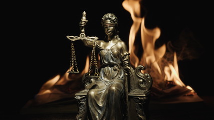 Fototapeta na wymiar Statue of Lady Justice on the background of the flame of a burning book