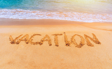 Vacation text on a beach. Vacation written in a sandy tropical beach. 