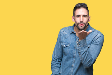 Young handsome man over isolated background looking at the camera blowing a kiss with hand on air being lovely and sexy. Love expression.