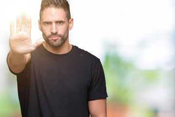 Young handsome man over isolated background doing stop sing with palm of the hand. Warning expression with negative and serious gesture on the face.