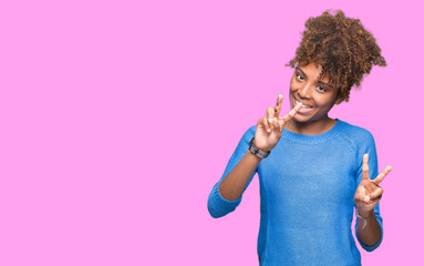 Beautiful young african american woman over isolated background smiling looking to the camera showing fingers doing victory sign. Number two.