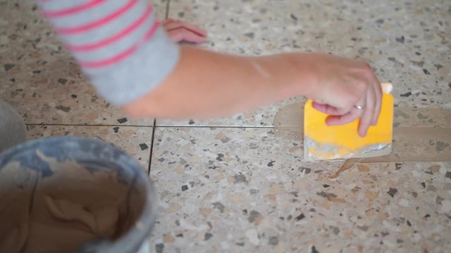 Repair and decoration of apartments and houses. woman fugues seams tiles in the bathroom