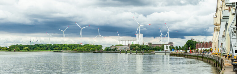 Wind turbines over cloudy sky on the bank of the river Scheldt, Antwerp, Belgium 2019.