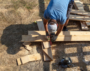 A worker cuts a wooden board at a construction site