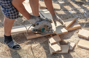 A worker cuts a wooden board at a construction site