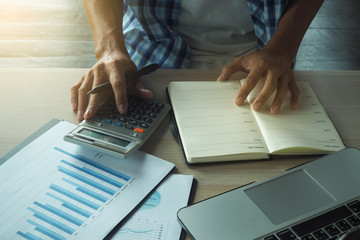 Businessmen are using a calculator. Calculate the average revenue of the company each month. Have charts and statistical data.