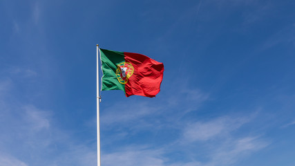 Beautiful large Portuguese flag waving in the wind against blue sky. Portuguese Flag Waving Against Blue Sky. Flag of Portugal waving, against blue sky