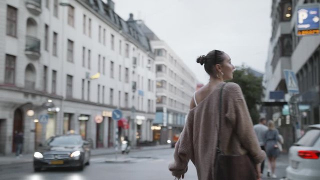A young confident woman turns around with her shopping as a car drives by