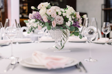 Luxurious fresh flowers in a glass vase decorate the wedding dining table