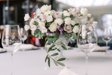 Stylish decor and flowers of a modern wedding. Table number on the transparent stand.