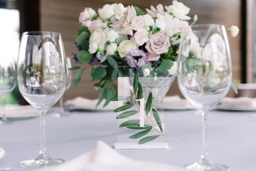 Champagne glasses, table number with number one and beautiful wedding flowers decorate the table at the wedding banquet.