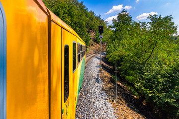 Train ride, view from a window. Old train passing green vegetation. View from the window. Traveling by train to sunset. Sunset scenery and a train gilded by sun, view from a train window. Czechia.
