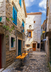 Obraz premium Narrow street in historic town Trogir, Croatia. Travel destination. Narrow old street in Trogir city, Croatia. The alleys of the old town of Trogir are very picturesque and full of charm. Croatia.