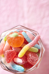 Jar full of jelly candy viewed from above on a pink background. Top view