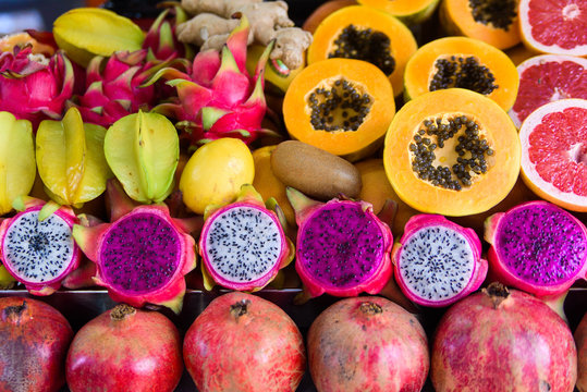 Exotic summer fruits laid out in shopping mall or market. Dragon fruit, pineapple, persimmon, mango, annona cherimola, pomegranate, carambola, grapefruit. Tropical fruits ready for juice.