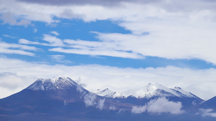 Fototapeta na wymiar View of the Andean volcanoes covered by clouds, Atacama Desert, Chile
