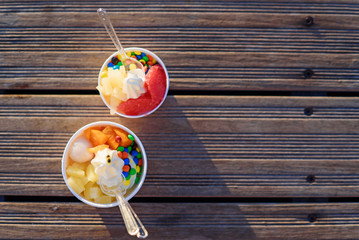 Two cups of ice cream with candies on sunset.