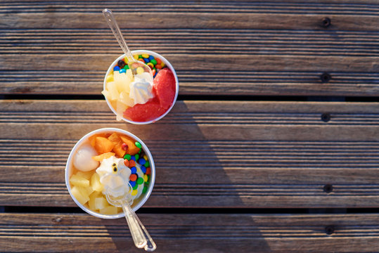 Two cups of ice cream with candies on sunset.