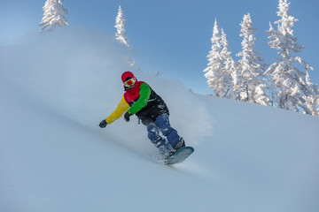 guy in a bright suit rides a snowboard in the snowy mountains. Snowboarding sport photo. Snowboarder in action on the track with fresh snow. very high resolution and photo quality