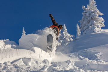 snowboarder snowboarding on fresh white snow with ski slope on Sunny winter day. very high...