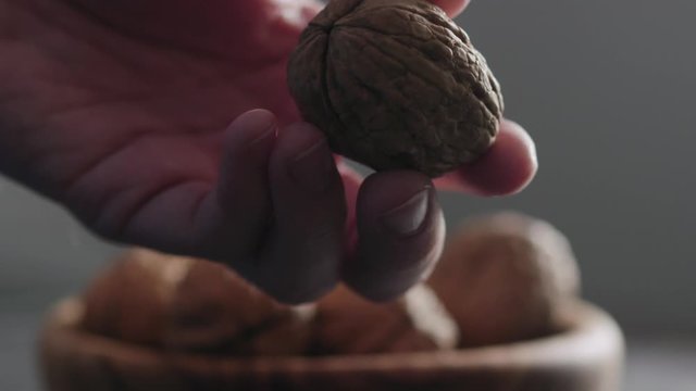 Slow motion closeup man hands opens walnut