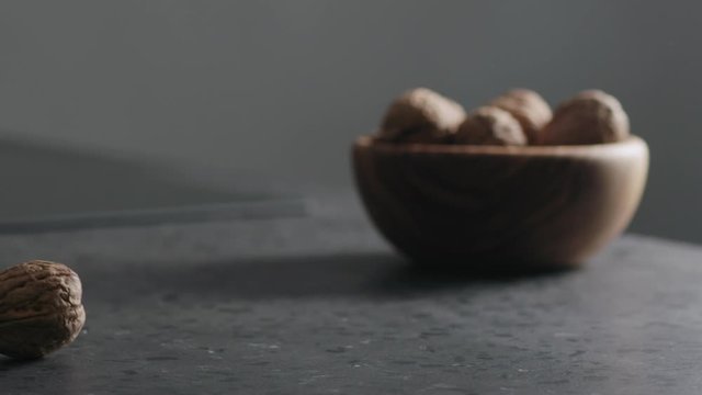 Slow motion shelled walnut rolls in frame on terrazzo countertop