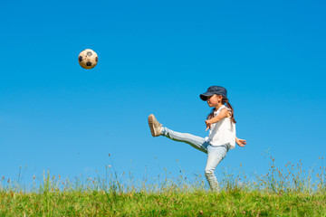 草原でサッカーボールを蹴る子供
