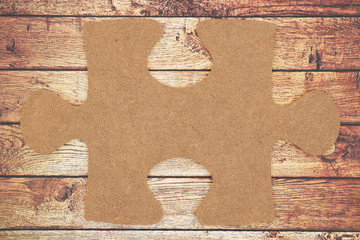 Brown blank cardboard puzzle piece on weathered  gunge textured wood background