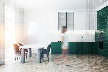 Woman walking in green kitchen with table