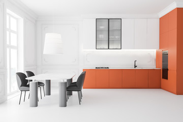 Side view of white and orange kitchen with table