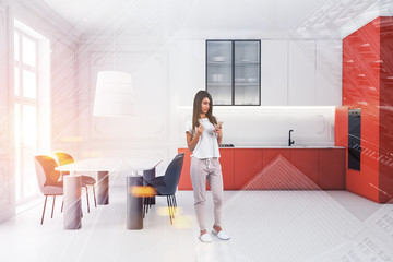 Woman with smartphone standing in orange kitchen