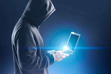 Side view of unrecognizable hacker with laptop