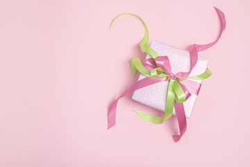 Gift box with green and pink ribbons on pink background with copy space. Holiday concept. Flat lay.  