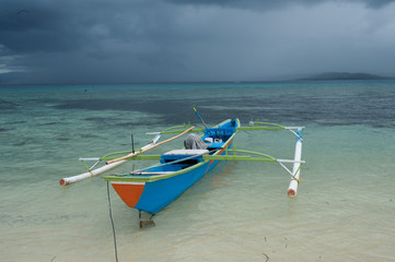 Outrigger canoe under tropical rain storm, Gangga Island, Sulawesi Indonesia.