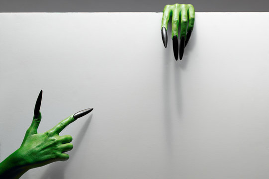 Halloween concept. Two green hands hold gray sheet of paper.