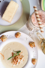 Conceptual cream soup in a white plate on a white table in a restaurant, cool plan. space