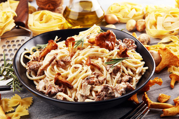 pasta with organic chanterelles. portion of spaghetti pasta with fried chanterelles in a creamy garlic sauce with cheese on a table